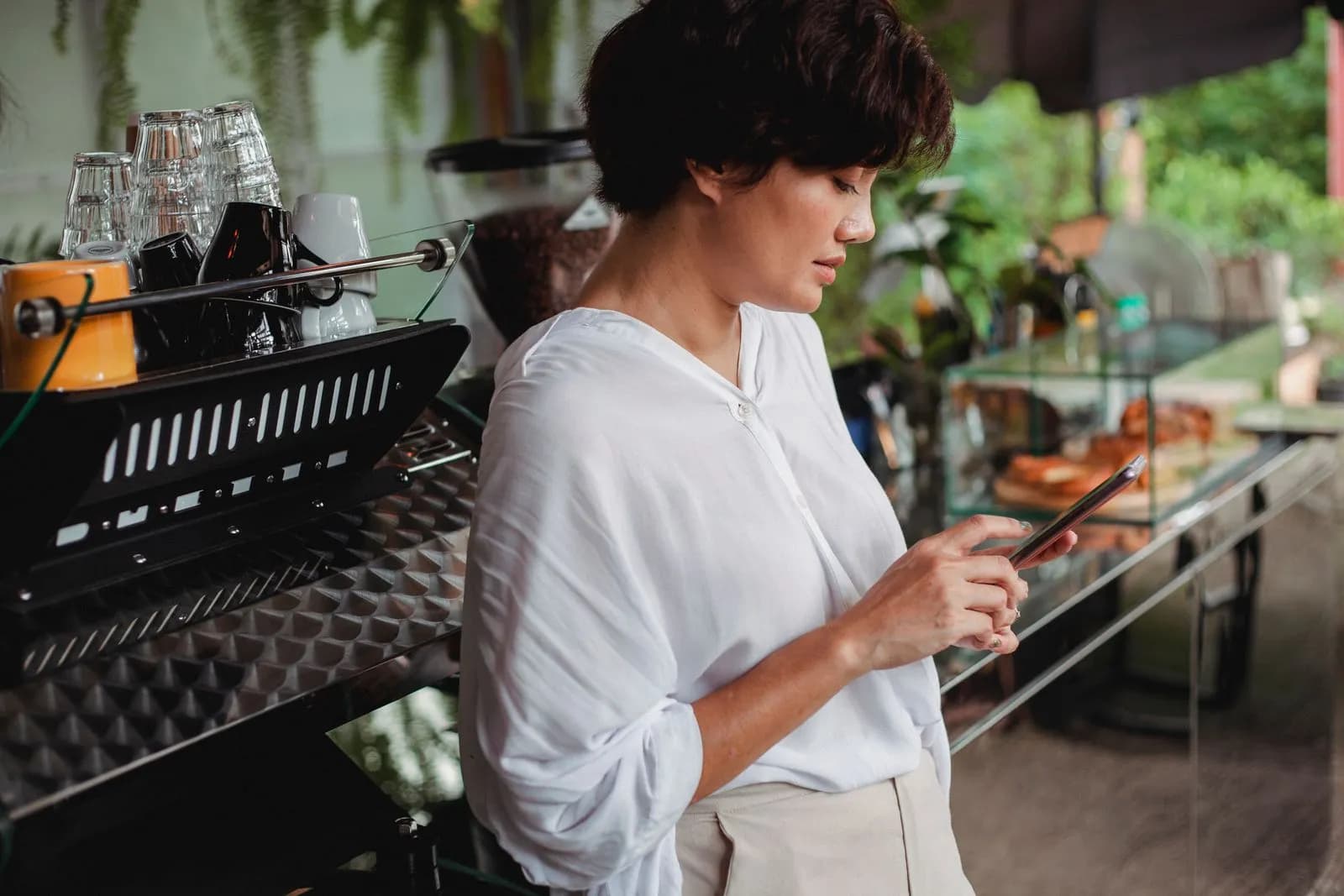 A woman in a café typing a post on her phone.